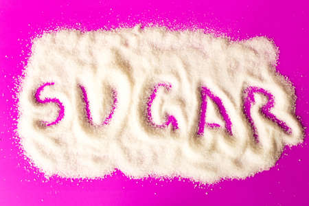 The inscription sugar on the pile of white sugar. Close up. On purple background.の写真素材
