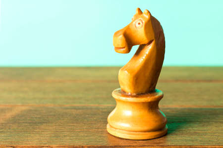 Chess horse on a wooden table. On a turquoise background. Close up.の写真素材