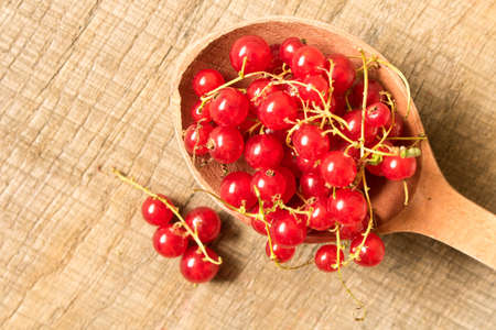 Fresh red currant in an old wooden spoon on a wooden table. The concept of natural food.