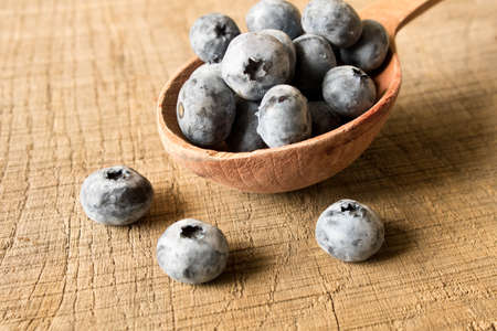 Fresh blueberries in a wooden spoon. On an old wooden table. The concept of natural food . Close up.の写真素材