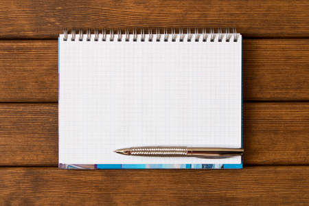 Clean sheet of notebook with pen on wooden office Desk . With empty space for text.の写真素材