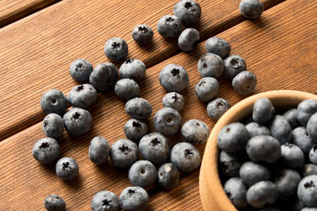 Fresh blueberries on a wooden table in a wooden plate. Close up. The concept of natural food.の写真素材