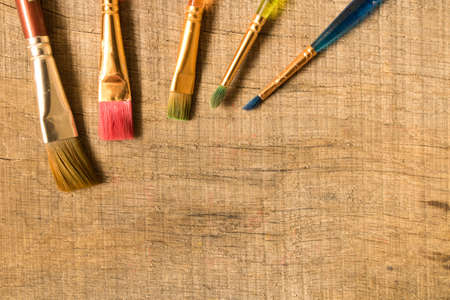 Different paint brushes on the old wooden table . The view from the top. Creative concept.の写真素材
