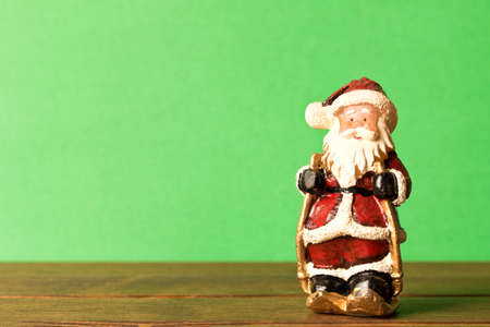 Funny toy Santa on green background. With empty text space. The concept of Christmas.