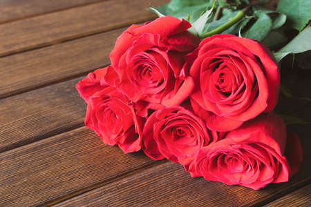 A beautiful rose on a wooden table. Conceptual design for greeting card.