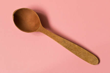Old wooden spoon. Isolated on pink background.の写真素材