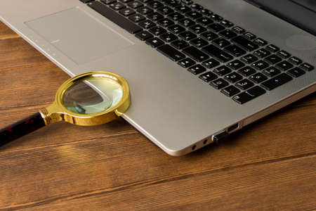 Magnifying glass on the laptop keyboard. The concept of information search on the Internet.の写真素材