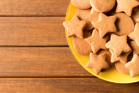Top view of freshly made cookies in a yellow plate on a wooden table. Close up.の写真素材