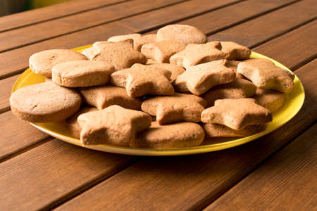 Freshly made cookies in a yellow plate on a wooden table. Close up.の写真素材