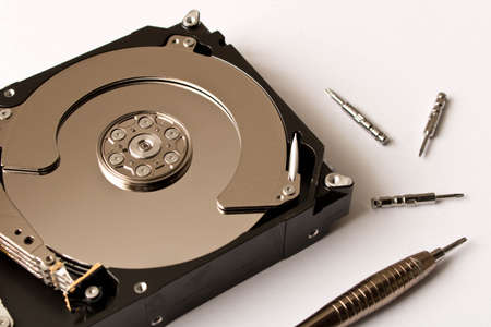 The disassembled hard disk with a variety of screwdrivers. Close up.