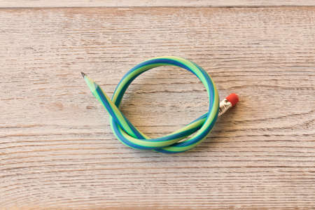 Flexible pencil on old wooden table . Bending pencil.