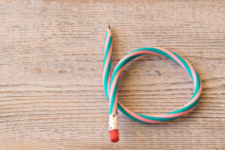 Flexible pencil on old wooden table . Bending pencil.