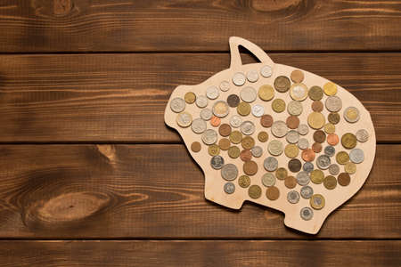 Many different coins on wooden pig. The concept of saving money