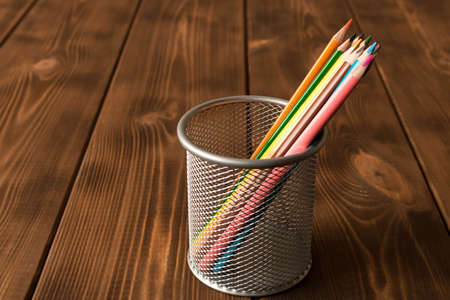 Set of colored pencils in a metal Cup on a wooden tableの写真素材