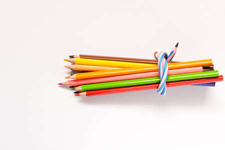 A set of colored pencils tied with a flexible pencil . Isolated on white background
