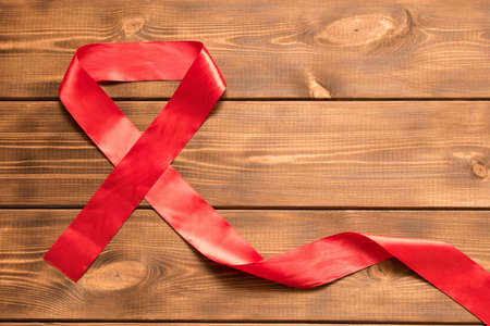 Red aids ribbon.  Isolated on wooden background with empty space for text.