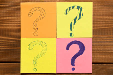 Different colored stickers with questions on wooden background. Concept of idea development.