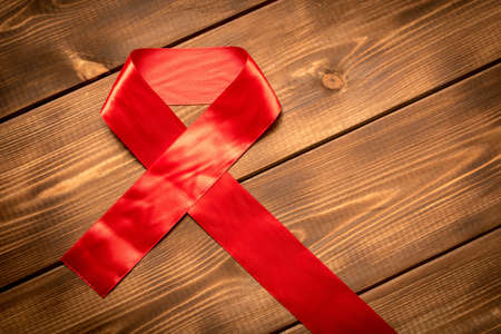 Red aids ribbon.  Isolated on wooden background with empty space for text.の写真素材