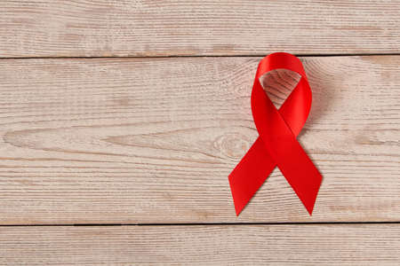 Red aids ribbon.  Isolated on wooden background with empty space for textの写真素材