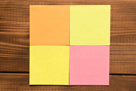 Different colored stickers on a wooden background. Empty text space.