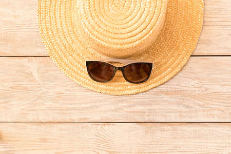 Sunglasses and a straw hat on a wooden table. The concept of summerの写真素材