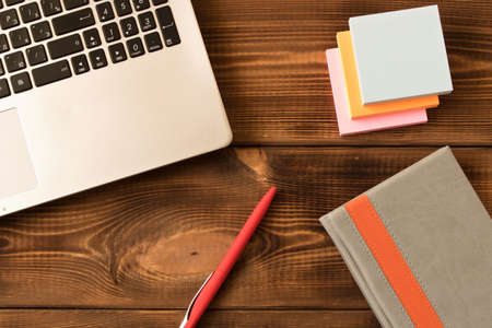 Laptop, notebook and pen on wooden table. Various office supplies on wooden backgroundの写真素材