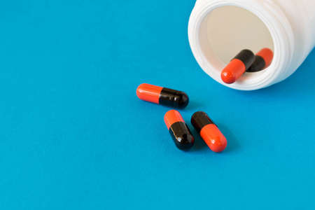 A bottle of pills scattered on blue background . Birth control pills