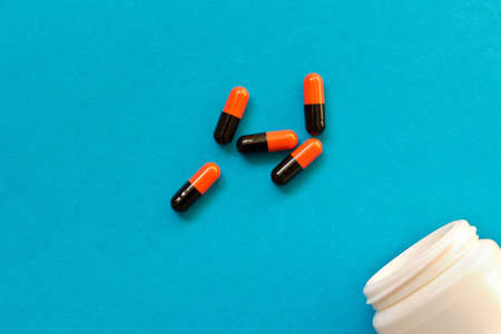 A bottle of pills scattered on blue background. Birth control pills