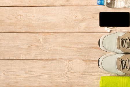 Gray running shoes and fitness accessories on wooden background. Empty text spaceの写真素材