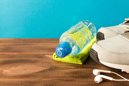 Gray running shoes and fitness accessories on wooden table. Empty text space