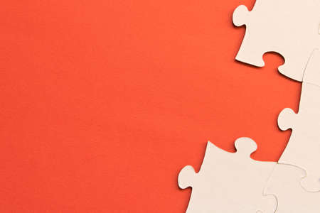 White jigsaw puzzles on red background. The concept of development of thinking. The concept of teamworkの写真素材