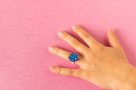 Funny ring on a little girl's hand. Isolated on pink backgroundの写真素材