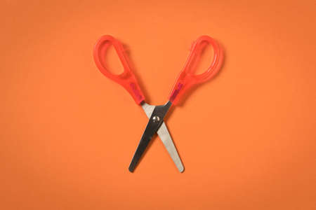 Scissors on an orange background. Colored baby scissorsの写真素材