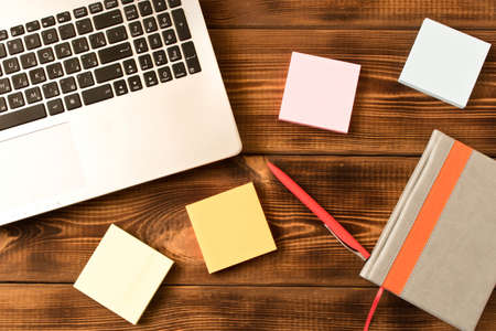 Laptop, notebook and pen on wooden table. Various office supplies on wooden backgroundの写真素材