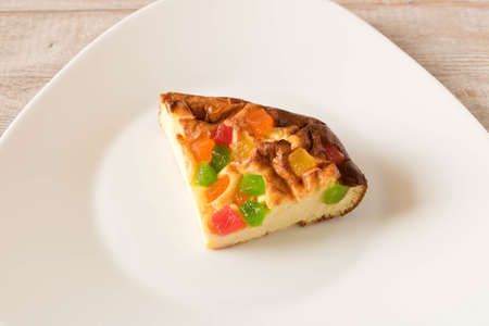 A piece of cottage cheese casserole with candied fruits on a white plate. Close upの写真素材