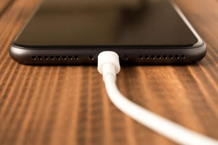 Smartphone on charge. On the  wooden table. Close upの写真素材