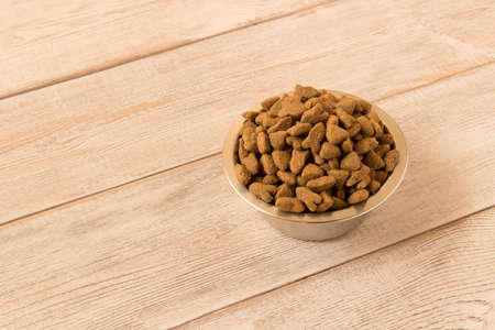 Bowl with dog food on a wooden table. Close up