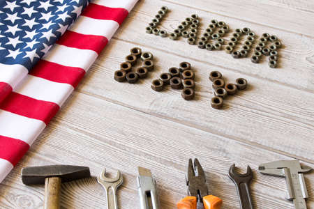 Labor day. American flag and Inscription labor day and various tools on a light wooden backgroundの写真素材