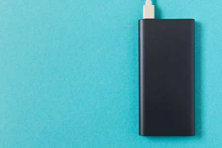 Black power Bank with adapter for charging mobile devices on a blue backgroundの写真素材