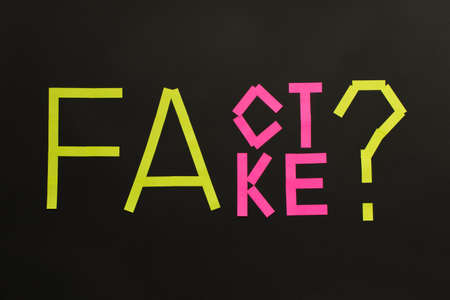 Fake News concept. The inscription FACT and FAKE on a black backgroundの写真素材