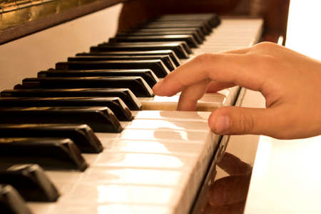 The girl's hand on the piano keys. Piano keys background. Selective focusの写真素材