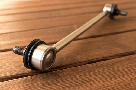 New car parts. Stabilizer link. Isolated on wooden background.の写真素材