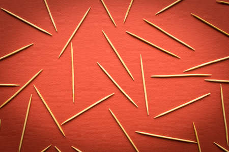 Many wooden toothpicks scattered on a red background. Abstract background for the design. Selective focusの写真素材