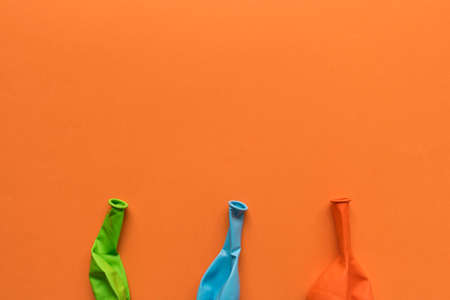 A few deflated multicolored balloons on an orange backgroundの写真素材