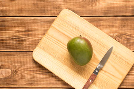 Mango fruit and a knife on a wooden table. Close upの写真素材