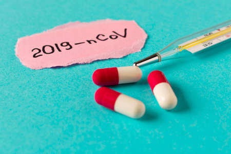 Coronavirus. The inscription 2019-nCoV on a piece of paper and several pills on a blue background....