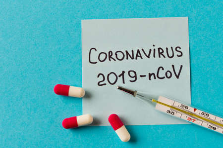 Coronavirus. The inscription 2019-nCoV on a piece of paper, a thermometer and several pills on a...