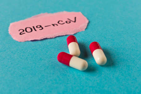 Coronavirus. The inscription 2019-nCoV on a piece of paper and several pills on a blue background....