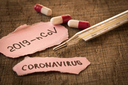 Coronavirus. 2019-nCoV. Thermometer and the inscription coronavirus on a sheet of paper on a wooden...