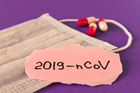 Coronavirus. 2019-nCoV. Protective medical mask and the inscription coronavirus on a piece of paper on a purple background. The concept of virus protection. Selective focus.の写真素材